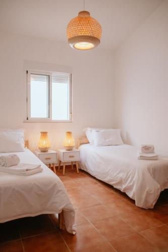 two beds in a white room with two lamps at Monte da Boavista de Cima - Casa de Campo