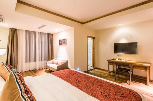 a hotel room with a bed and a desk and a television at The Apsara Lodge-Airport or TS Free pick-up over 3 nights in Yangshuo