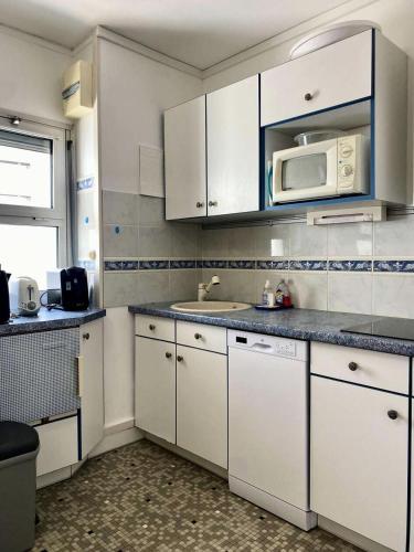 une cuisine avec des armoires blanches et un micro-ondes dans l'établissement Résidence Mogador - Arcachon - T1 avec balcon et vue mer MAE-7071, à Arcachon