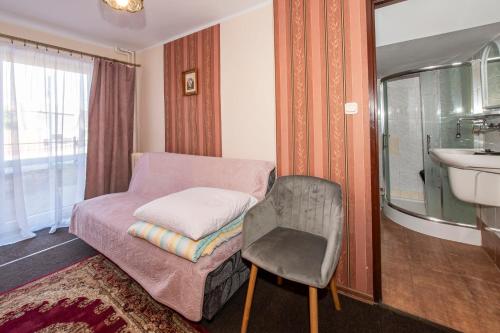 a room with a bed and a chair and a sink at O. W. Jodełka in Łeba