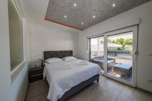 a bedroom with a bed and a large window and a tub at VILLA Juky in Kaštela