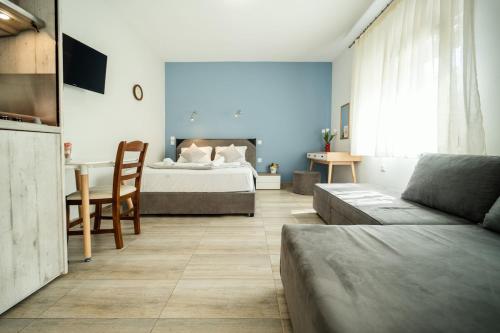 ein Schlafzimmer mit einem Bett, einem Tisch und einer Couch in der Unterkunft Seaside Studio in Nea Peramos, Sleeps 4 in Néa Péramos
