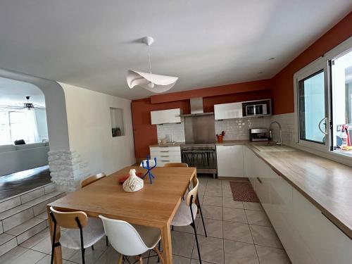 une cuisine et une salle à manger avec une table et des chaises en bois dans l'établissement Maison de Coeur - Futuroscope, à Jaunay-Clan