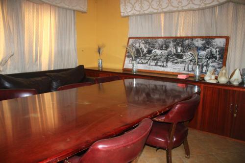 a dining room with a wooden table and leather chairs at EvehomeStay B&B in Soshanguve