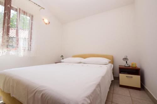 a bedroom with a white bed and a window at Apartments Milena in Stomorska