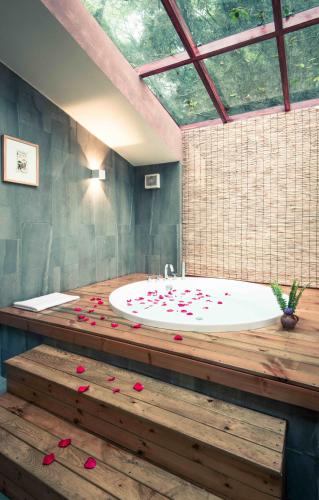 a bathroom with a tub with red rose petals on the floor at The Apsara Lodge-Airport or TS Free pick-up over 3 nights in Yangshuo