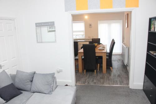 a living room with a couch and a dining room table at Tastefully furnished and Cosy 2-bedroom house in South Shields