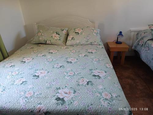 a bed with a blue comforter with flowers on it at Casa Lago Rapel, Las Cabras in Las Balsas