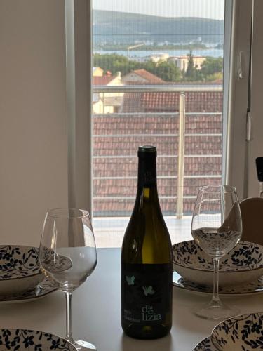 a bottle of wine sitting on a table with two glasses at Apartman Dejana in Tivat