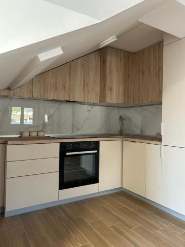 a kitchen with white cabinets and a black oven at Apartman Dejana in Tivat