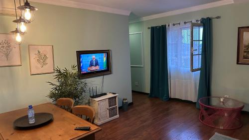 a living room with a table and a tv on the wall at Studio by Casa da Quinta in Funchal