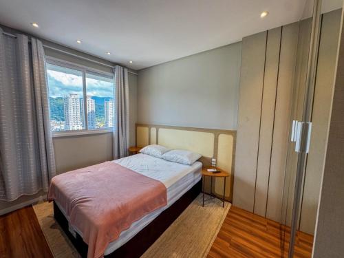 a bedroom with a bed and a large window at Apartmento luxo Itapema SC in Itapema