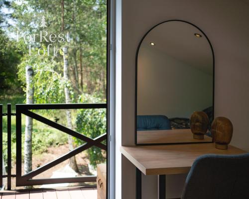 a mirror on a table in front of a window at ForRest Loft in Poręby Kupieńskie