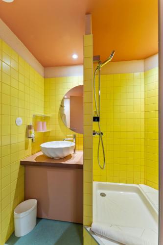 a yellow bathroom with a tub and a sink at greet hôtel Pont du Gard - Route d'Avignon in Estézargues