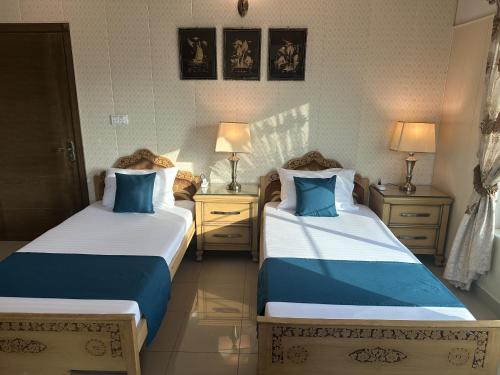 a bedroom with two beds with blue and white sheets at Stylish Luxe 2 BedroomLK Condo Close to GIGA Mall in Islamabad