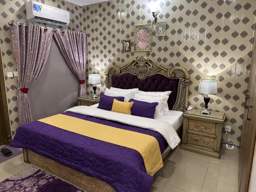 a bedroom with a bed with purple and yellow sheets at Stylish Luxe 2 BedroomLK Condo Close to GIGA Mall in Islamabad