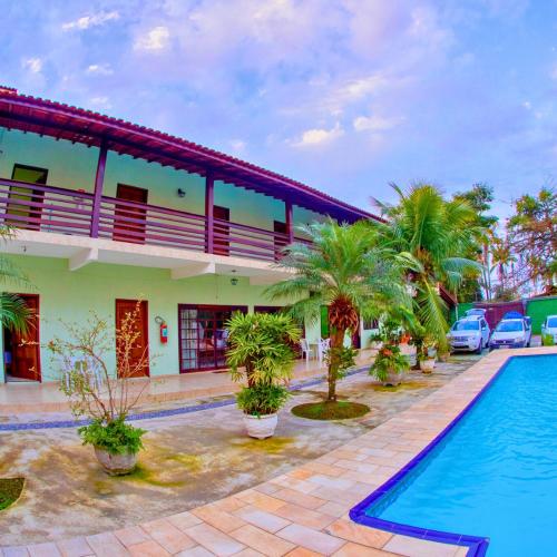 a hotel with a swimming pool in front of a building at Enseada Marwille Pousada in Guarujá