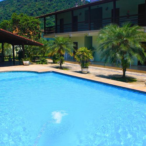 a large blue swimming pool in front of a building at Enseada Marwille Pousada in Guarujá