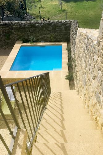 une piscine bleue à côté d'un mur en pierre dans l'établissement Old house, close to Uzès, à Argilliers
