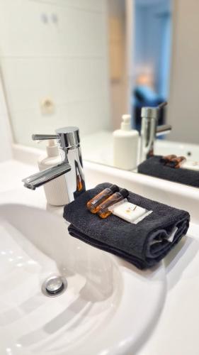 un lavabo de salle de bain avec une serviette noire et un robinet dans l'établissement Appartement 2P, balcon, parking proche mer, à Nice