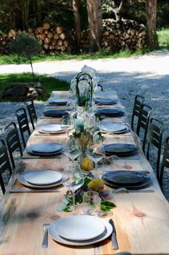 - une longue table en bois avec des assiettes et des verres à vin dans l'établissement Quiet Provencal bastide with pool close Lourmarin, à Lauris