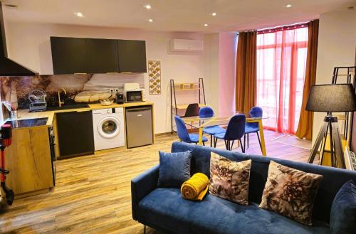 a living room with a blue couch and a kitchen at Mitrons - Apt A in Saint-Affrique