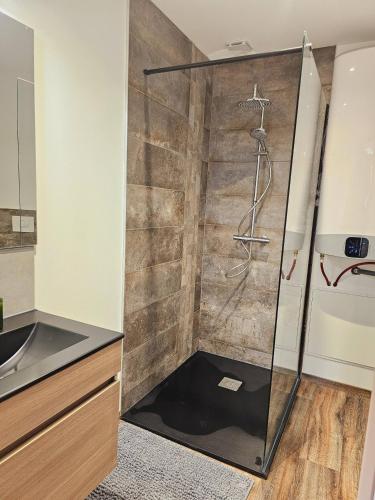 une douche avec une porte vitrée dans une salle de bain dans l'établissement Mitrons - 2A, à Saint-Affrique