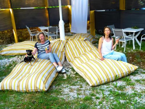 two women sitting on striped pillows with a dog at Relax Apartments Grazia in Funtana