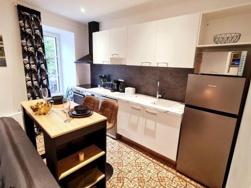 - une cuisine avec des placards blancs, une table et un réfrigérateur dans l'établissement Rep - 2A, à Millau