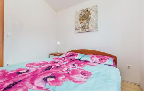 a bed with a blanket with pink flowers on it at MERTIK Apartment in Omišalj