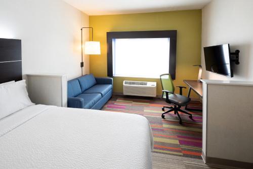 a hotel room with a bed and a couch at Holiday Inn Express & Suites Chicago West - St Charles by IHG in Saint Charles