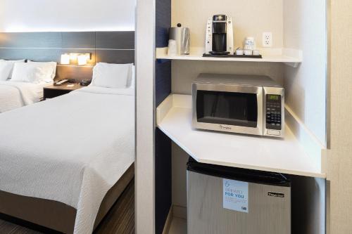 a small room with a bed and a microwave at Holiday Inn Express & Suites Chicago West - St Charles by IHG in Saint Charles