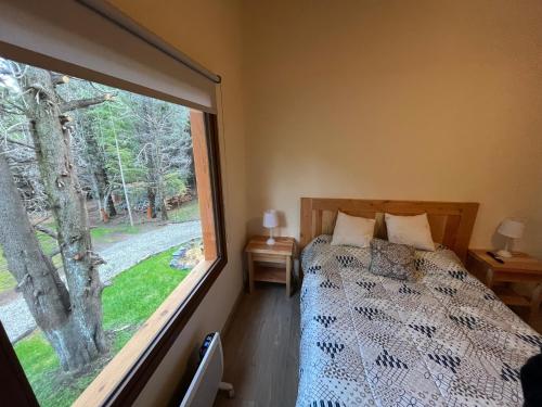 a bedroom with a bed and a large window at LOS HUEMULES - casa nueva en medio del bosque y a pasos del centro de la ciudad- in San Carlos de Bariloche