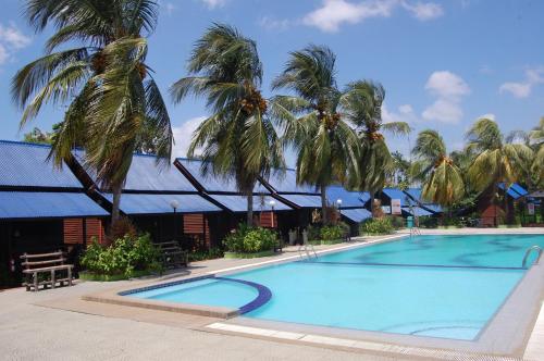 a large swimming pool with palm trees in front of a building at D'Village Resort Melaka in Melaka