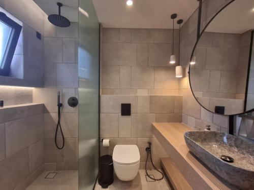 a bathroom with a toilet and a sink and a mirror at Panorama Studios & Apartments in Amoudi