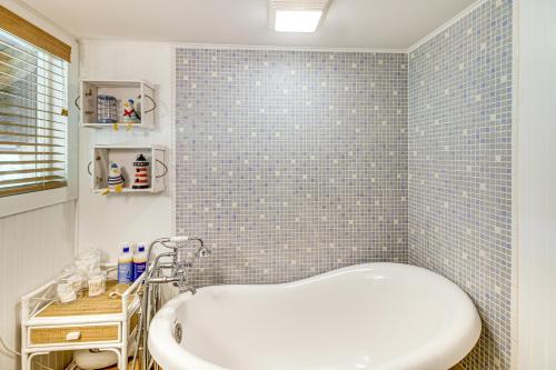 a bathroom with a tub and a blue tiled wall at Canal Across Street Family Cabin in Breezy Point! in Pequot Lakes