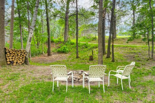 a group of three chairs and a table in the grass at Canal Across Street Family Cabin in Breezy Point! in Pequot Lakes