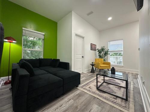 a living room with a black couch and a green wall at 30-A Inn & Suites in Santa Rosa Beach