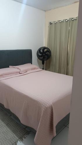 a bedroom with a bed with pink sheets and a window at Apartamento condominiofechado in Ananindeua