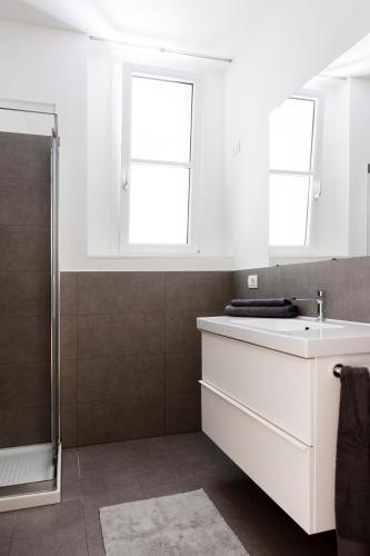 a white bathroom with a sink and two windows at La Residenza sul Mera in Chiavenna