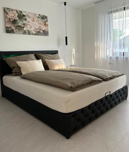 a large bed in a white room with avertisementatronatron at Casa Tandri am Rebenweg in Bermatingen