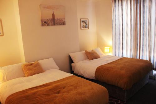 a hotel room with two beds and a window at Tastefully furnished and Cosy 2-bedroom house in South Shields