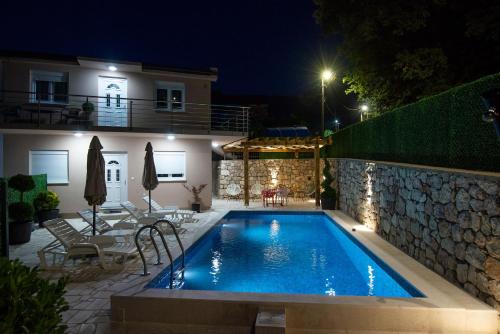 a swimming pool in front of a house at night at Apartmani Vesna in Ðuranovići