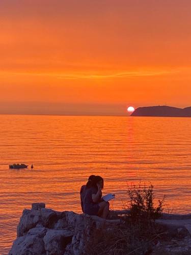 a woman sitting on a rock watching the sunset at Traceys 3 Apartments Borsh in Borsh