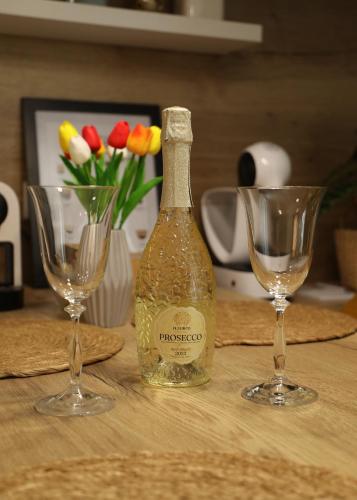 a bottle of champagne and two wine glasses on a table at Happy Island Luxury Apartman Sárvár in Sárvár
