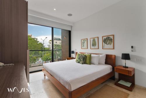 a bedroom with a bed and a large window at Luminous 1 Br. Steps away from the Beach in Playa del Carmen
