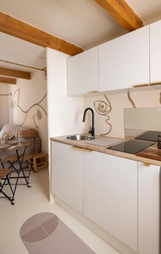 a kitchen with white cabinets and a sink and a table at CASA ANANTA Appartements bien-être aux portes du Verdon Refuge slow Life et sensoriel jusqu à 12 pers in La Garde