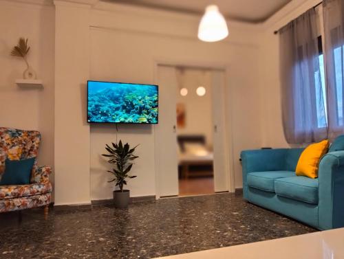 Una sala de estar con un sofá azul y un televisor de pantalla plana. en ilios - urban suite, city center, en Heraclión