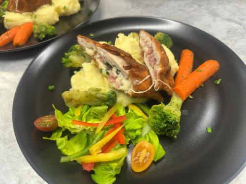 a black plate of food with vegetables and meat at Salgó Hotel in Salgótarján