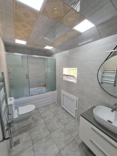 a bathroom with a sink and a toilet and a mirror at Gulu Cottage House in Mərdəkan